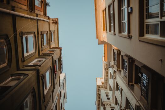 A unique low-angle view of urban residential buildings against a clear blue sky.