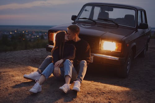 Photograph of a Couple Kissin in Front of a Car