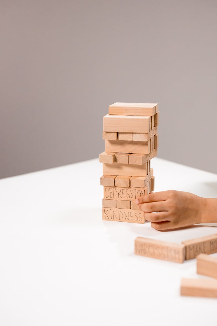 A Person's Hand Near Jenga Pieces