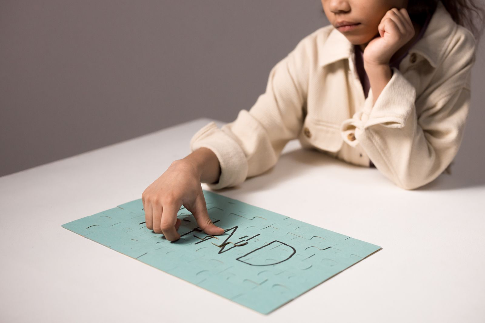 Child concentrating on a colorful tabletop puzzle during thoughtful indoor play