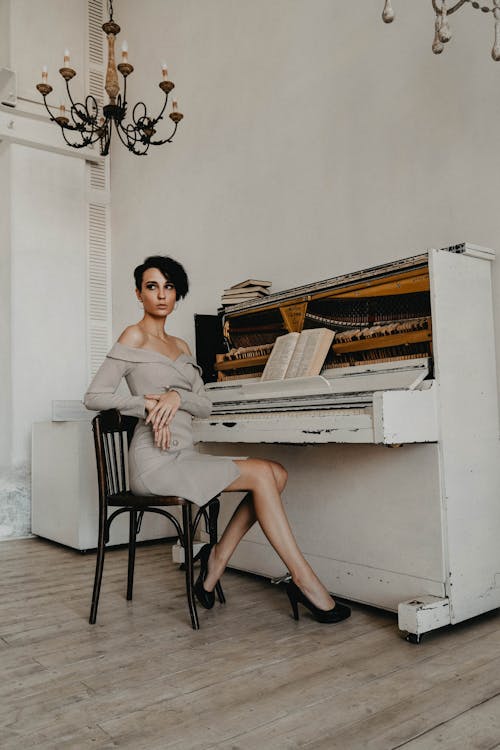 A Woman in a White Dress Sitting on a Chair in Front of a Piano