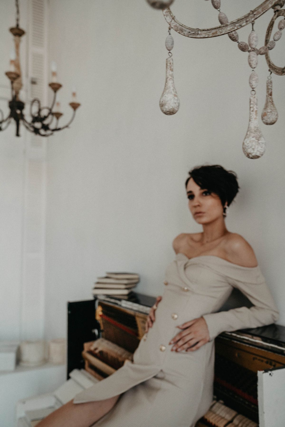 A woman in an off-shoulder dress leaning on a piano — the quiet sensuality of the bared shoulder