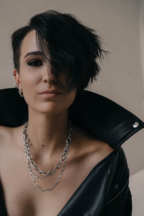 Free Close-up portrait of a stylish woman with short hair and chain necklace in a leather jacket. Stock Photo