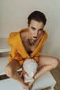 Woman in Yellow Top Holding White Head Statue
