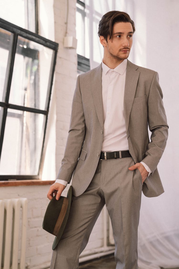 A Man In Gray Suit Holding A Black Hat