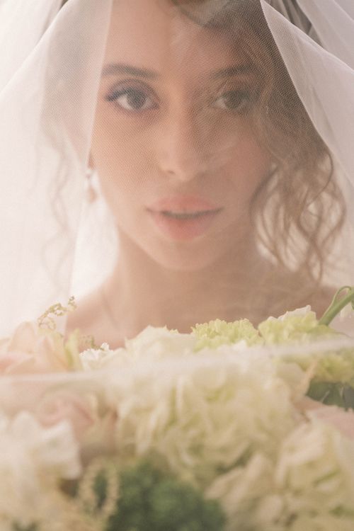 Free A beautiful bride in a veil with a floral bouquet exudes elegance on her wedding day. Stock Photo