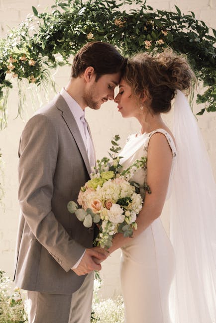 Bride and groom embrace under floral arch, exchanging vows for a new beginning.
