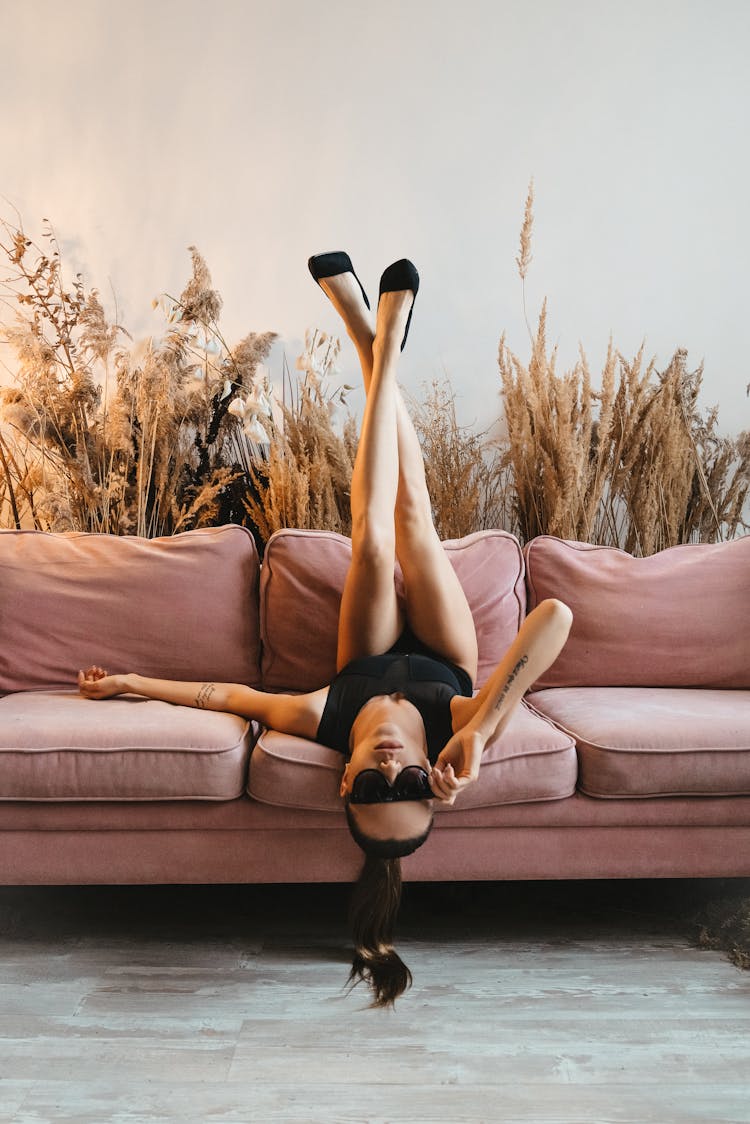 Woman Lying Upside Down With Legs Up On The Couch 