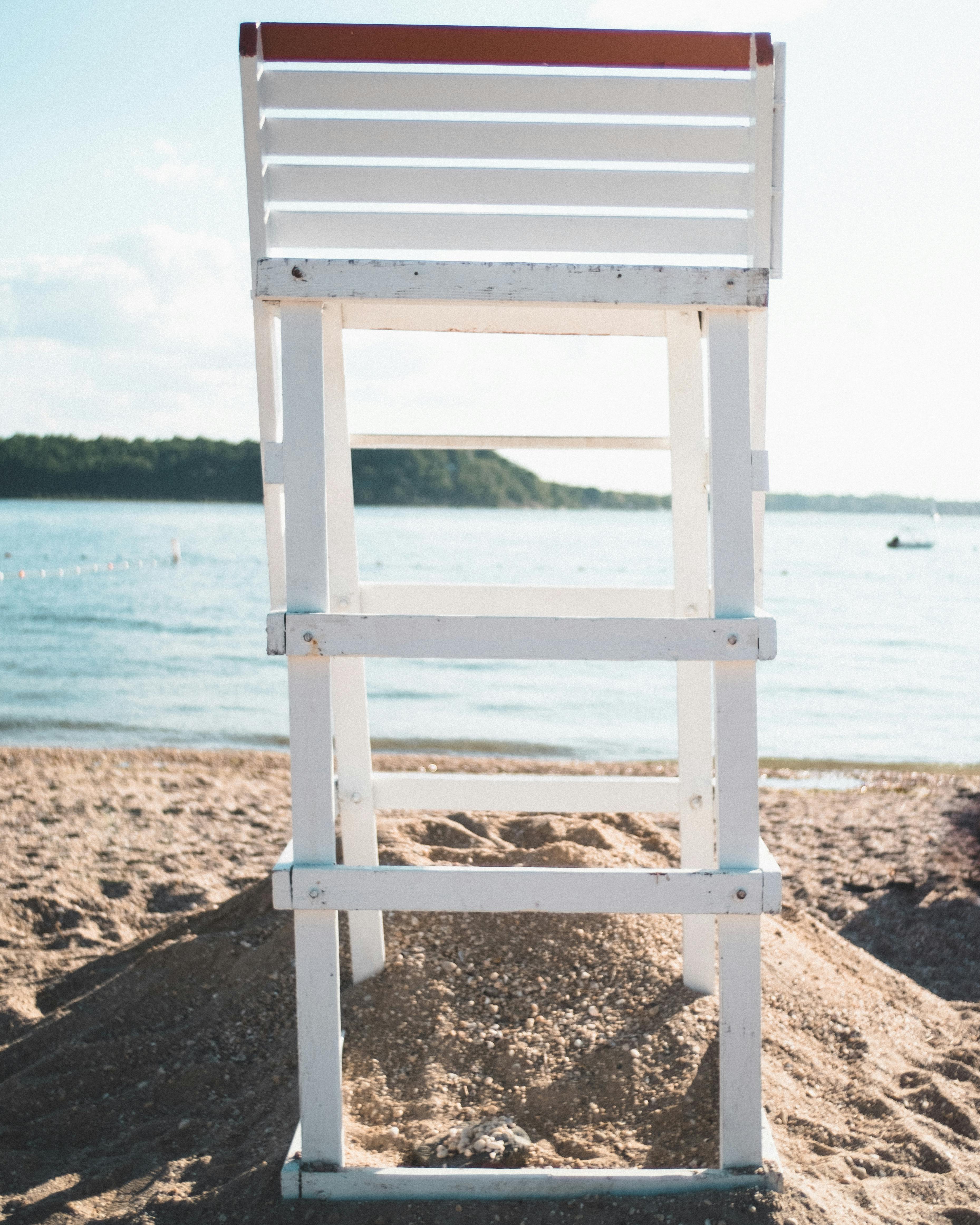 A lifeguard tower stands on a serene beach with a view of the calm sea under a clear sky.