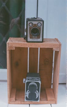 Vertical shot of vintage cameras in a wooden crate, showcasing retro design.