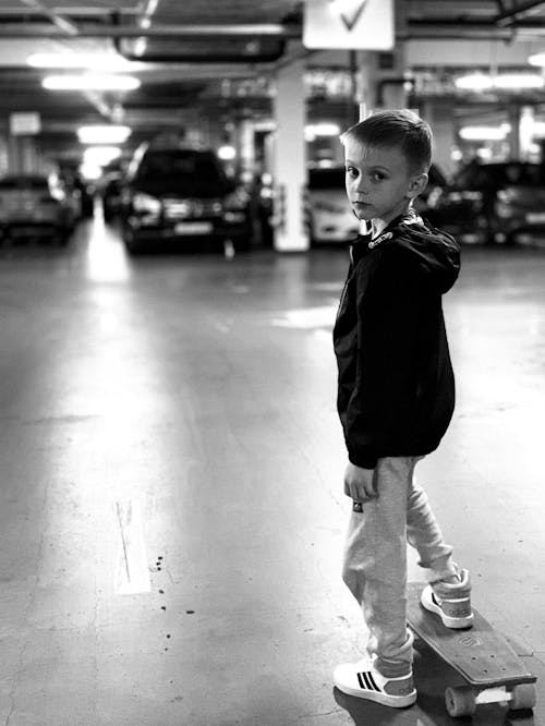 Free Grayscale Photo of Boy Standing on a Penny Board  Stock Photo