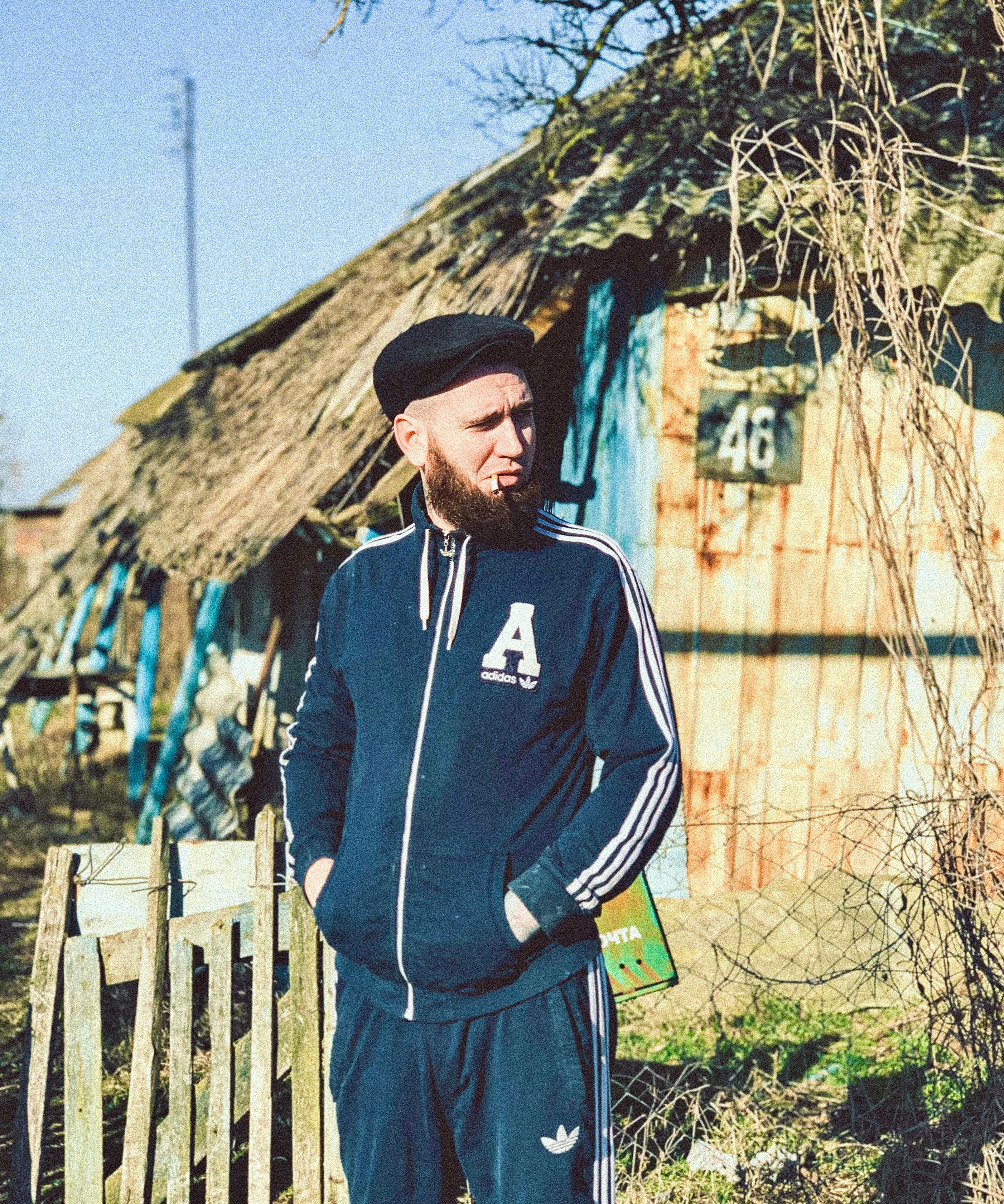 A man in a tracksuit stands outdoors in Slavyansk-na-Kubani, Russia, on a sunny day.