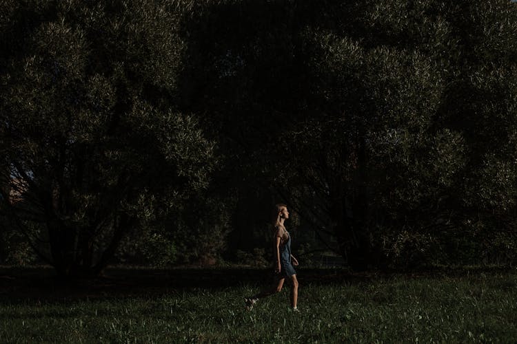 A Woman Walking On A Grassy Field At Night