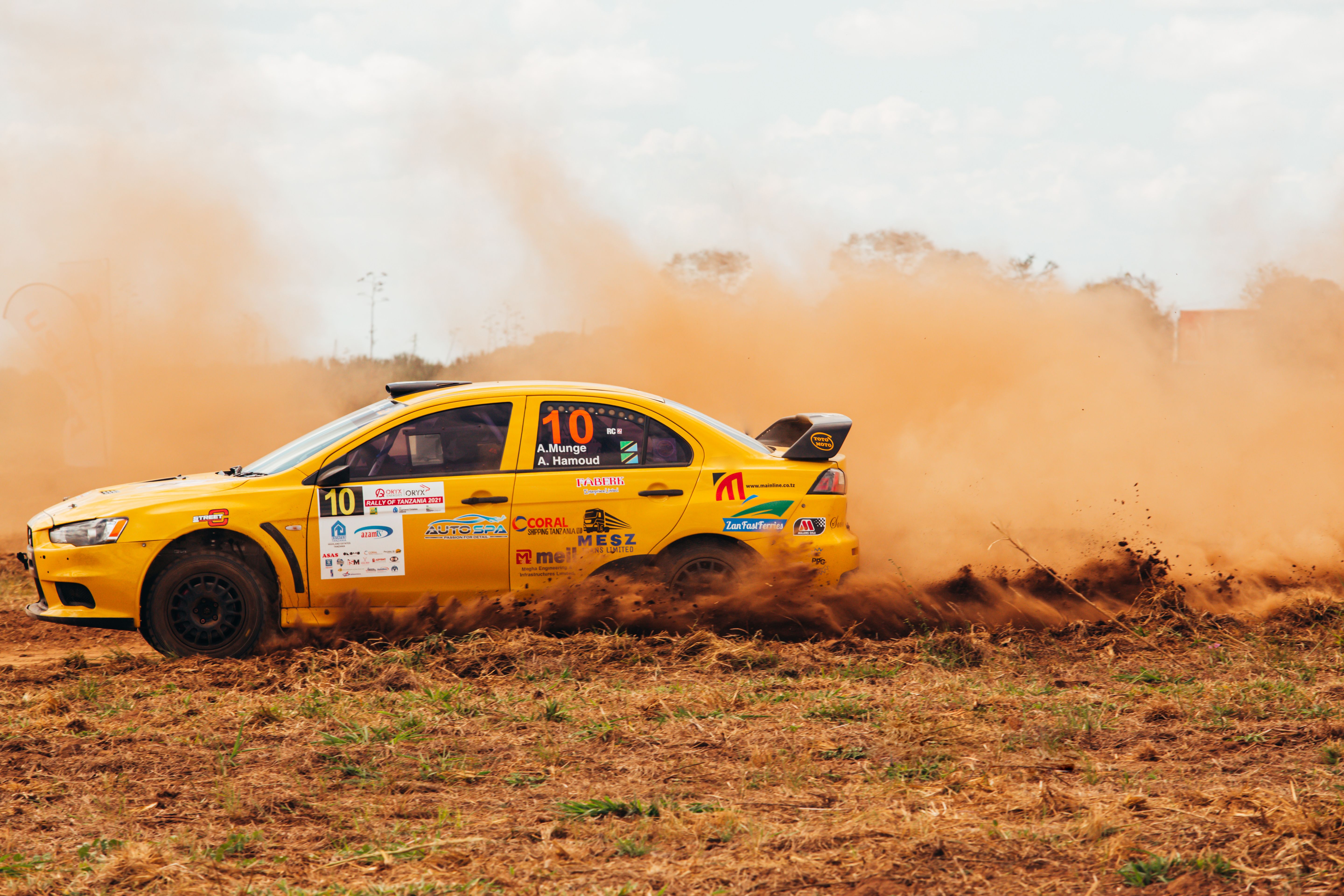 winger accelerating through yellow cones during a high-intensity football sprint drill, coach timing every repetition