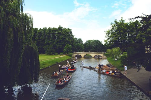 Group of People Ride on Jon Boats Near Bridge