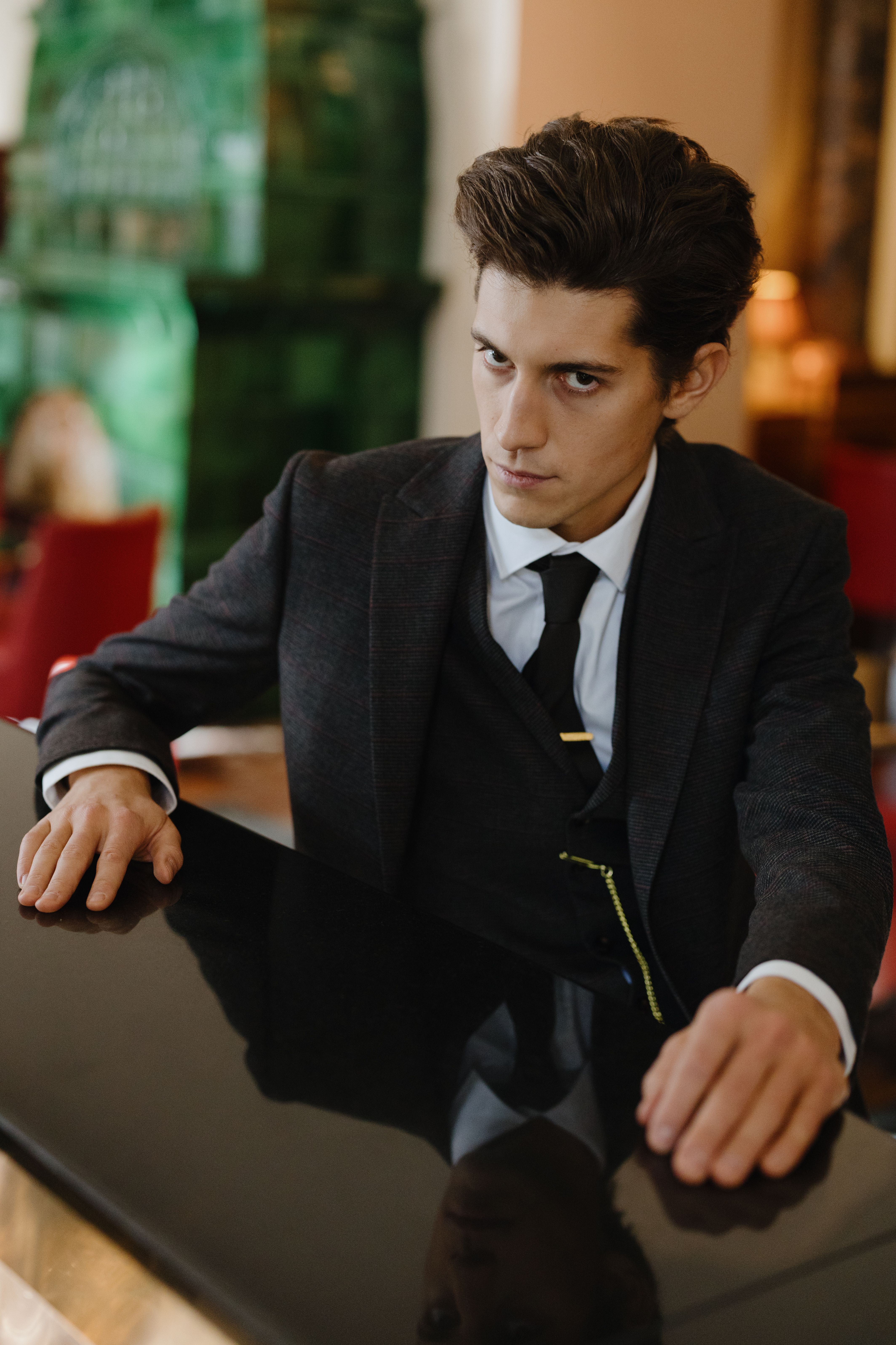 Man in sleek black suit seated at a luxurious bar counter, exuding elegance and sophistication.