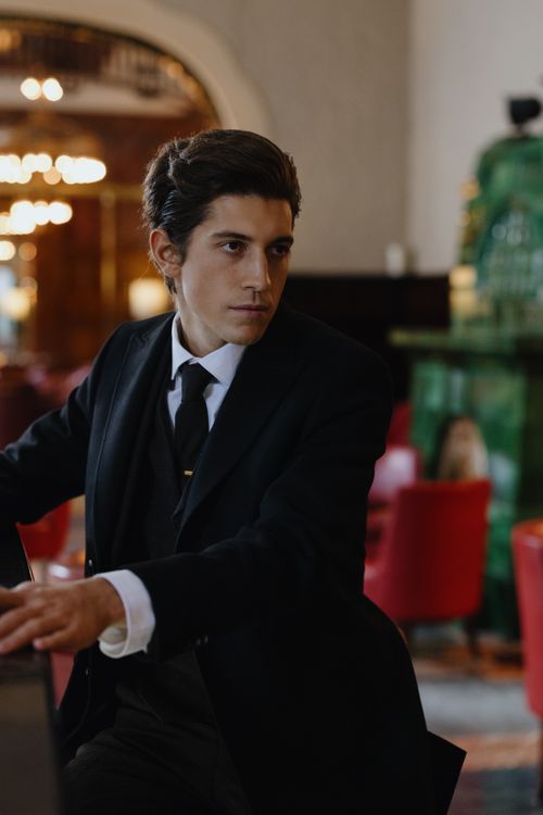 Free Refined gentleman in a black suit seated in an upscale lounge, exuding sophistication and style. Stock Photo