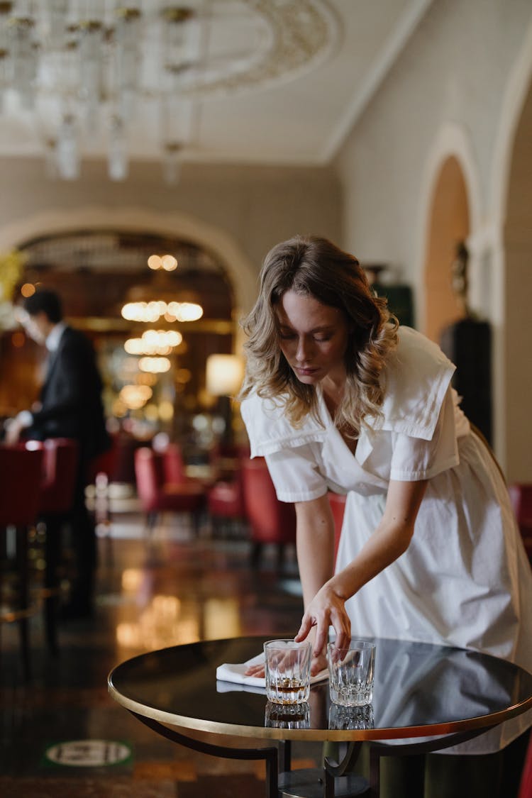 Woman In White Dress Wiping The Table