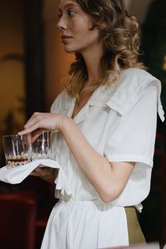 Elegant waitress serving drinks in a chic restaurant setting.