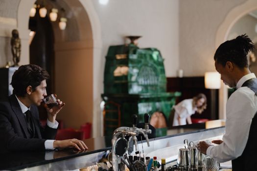 An intimate bar scene featuring a customer enjoying whisky and a bartender at work.
