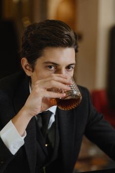 Sophisticated man in suit savoring a fine whiskey indoors.