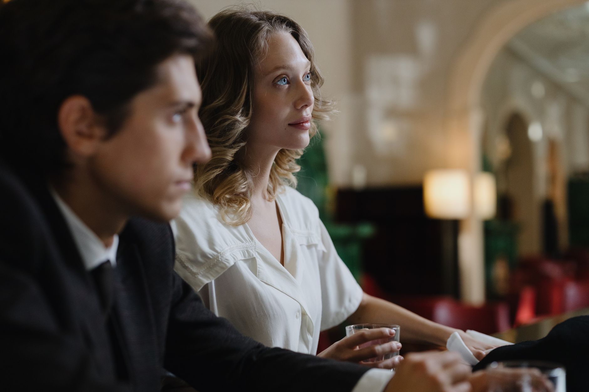 A stylish man and woman seated in a refined lounge, showcasing elegance and sophistication.