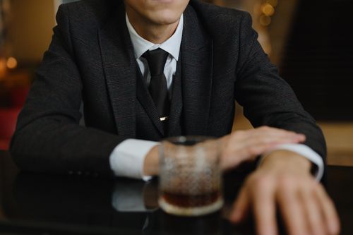 Free Close-up of a man in a suit enjoying a glass of whiskey at a bar, showcasing elegance and relaxation. Stock Photo