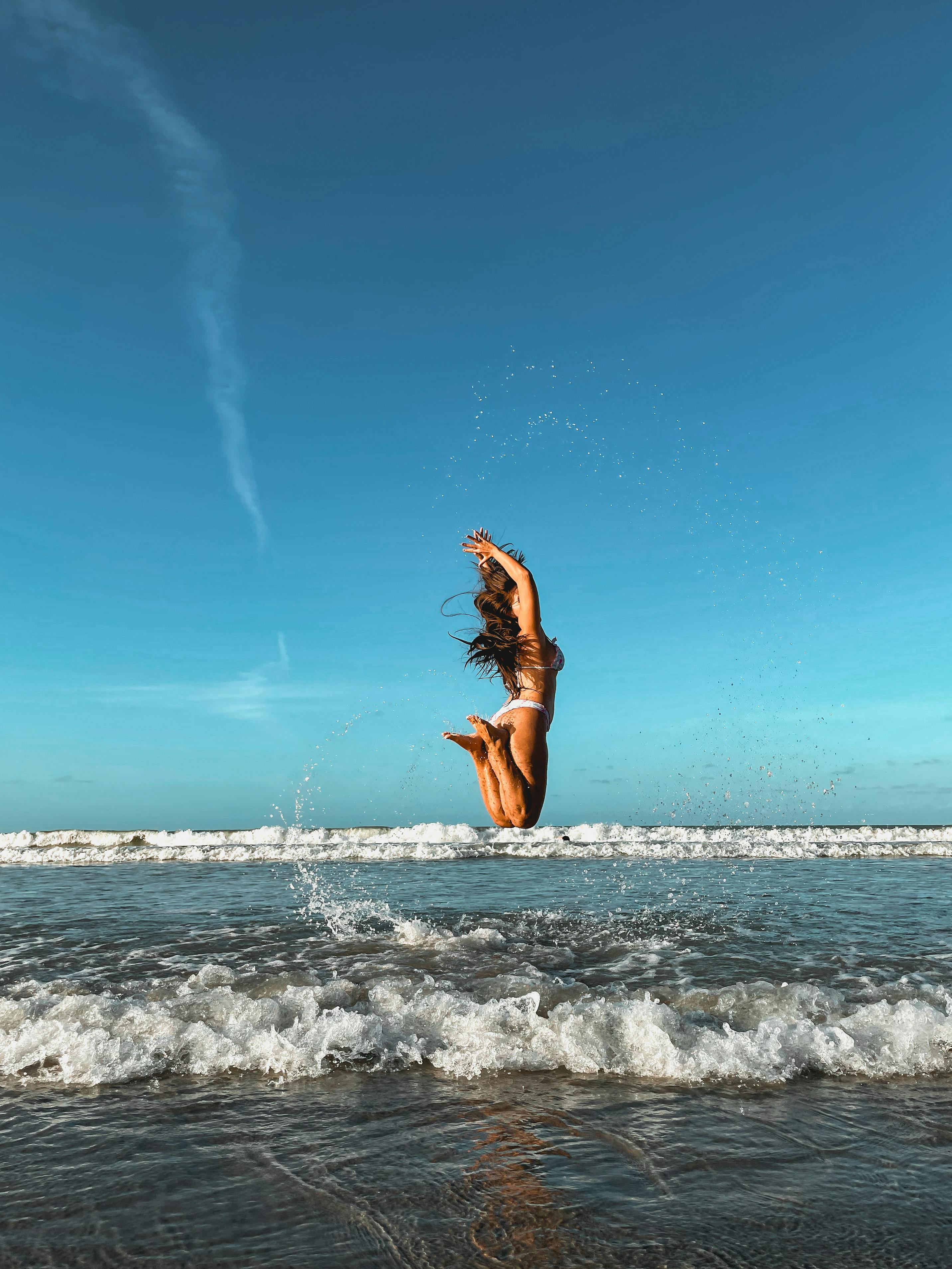 A Woman in White Bikini Jumping on the Beach · Free Stock Photo