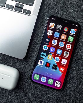 Flat lay of a smartphone, laptop, and earphones on a grey surface. Perfect for tech and gadget themes.