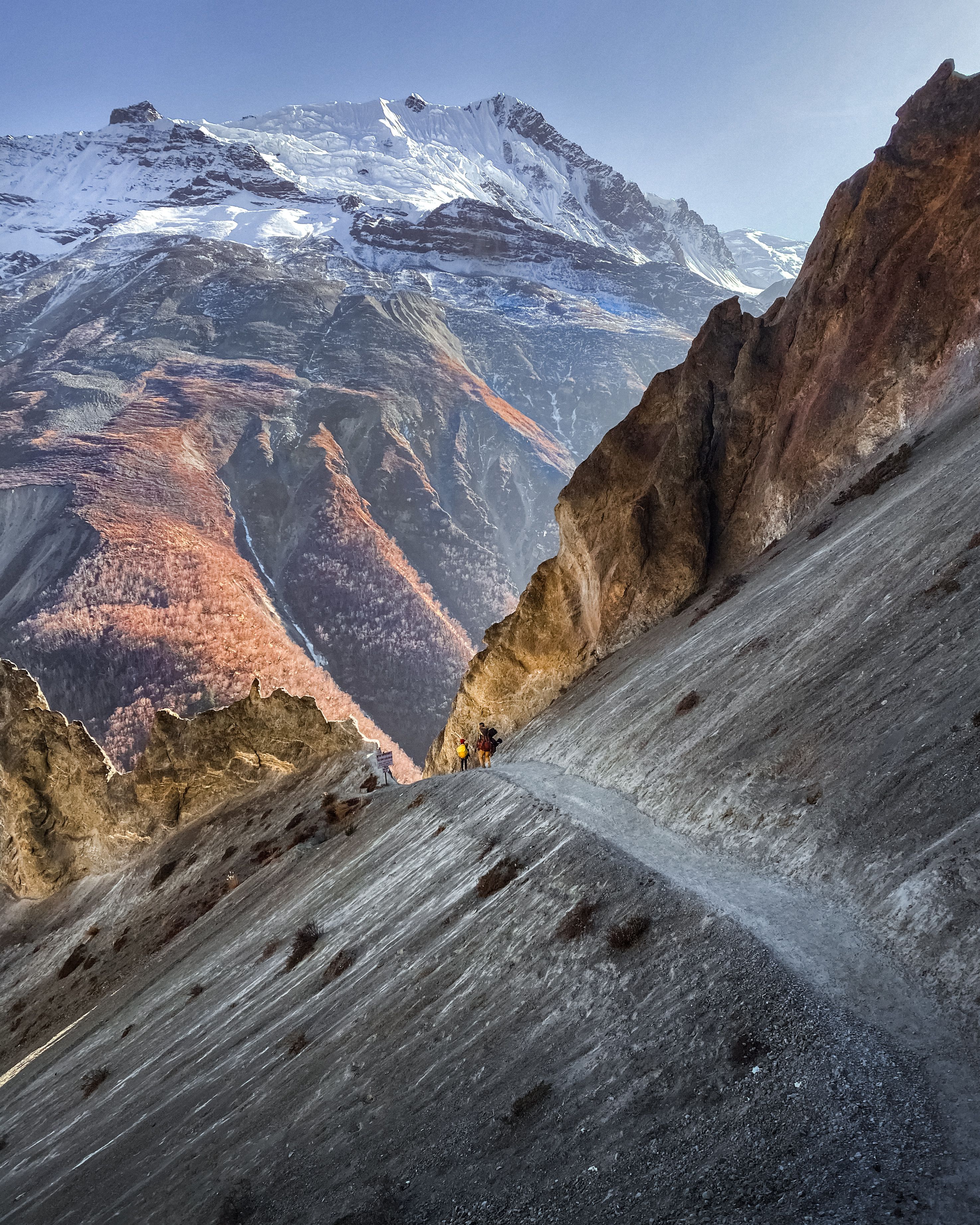 A breathtaking scene of a winter hiking trail in Khangsar, Nepal, with snow-capped peaks.