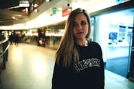 一名年轻女子站在光线充足的购物中心走廊里，背景模糊