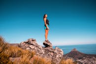 一位爱冒险的女人自信地站在岩石上，俯瞰开普敦的风景