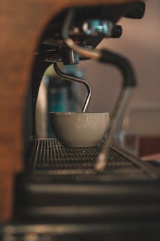 A detailed view of an espresso machine brewing a coffee cup indoors. Ideal for cafes.