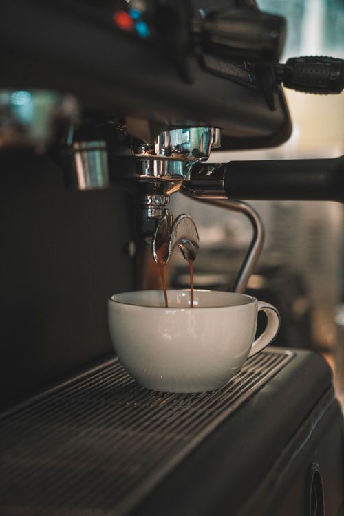 Free Close-up shot of a fresh espresso being poured into a white cup from a coffee machine. Stock Photo