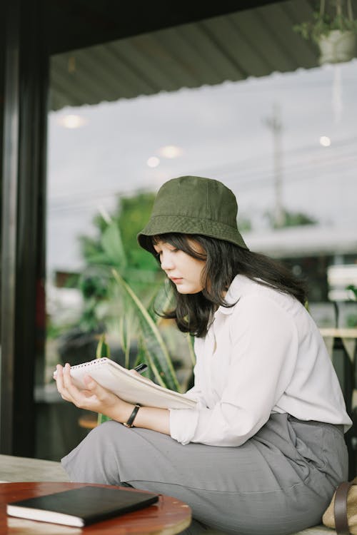 Free Woman in Green Bucket Hat reading Book  Stock Photo
