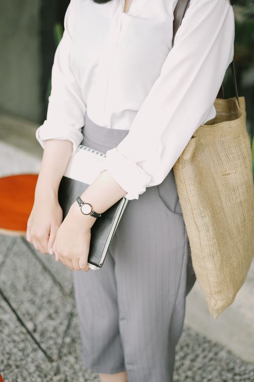 Free Woman in business attire holding a notebook with a jute bag in an office setting. Stock Photo