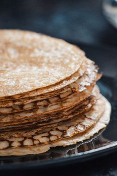 Delicious stack of freshly made pancakes on a dark plate, captured in a close-up shot.