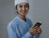 Man in Blue Dress Shirt Holding Brown Book