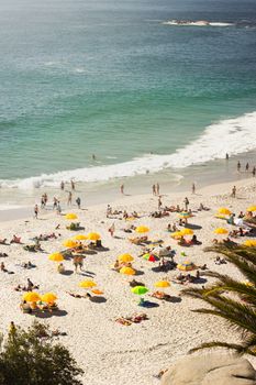 Aerial view of Clifton Beach with vibrant yellow umbrellas and beachgoers enjoying the sun and waves.