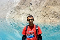 一名年轻人戴着墨镜、背着背包，在迷人的山间湖泊旁欣赏风景