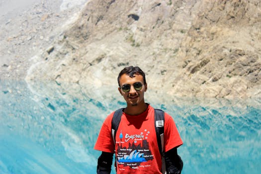 一名年轻人戴着墨镜、背着背包，在迷人的山间湖泊旁欣赏风景