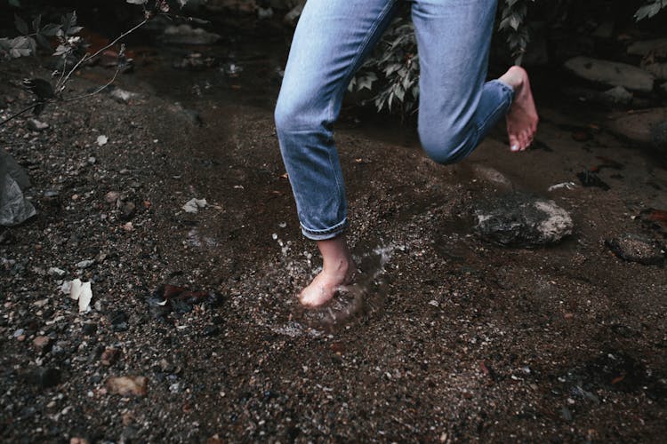 Person In Denim Pants Hopping Barefoot On Shallow Water