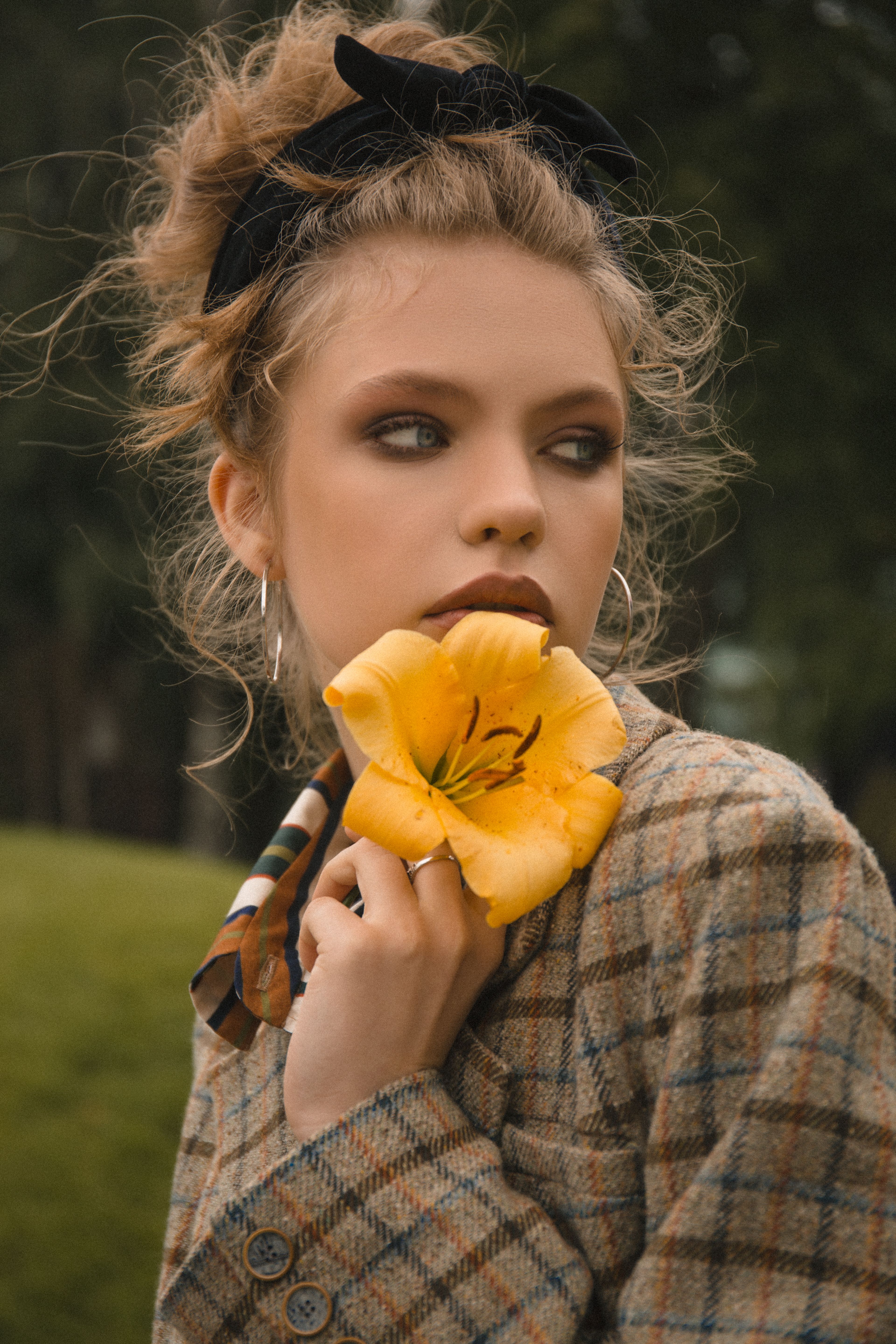 Stylish woman with a yellow lily in hand, showcasing beauty and nature in harmony.