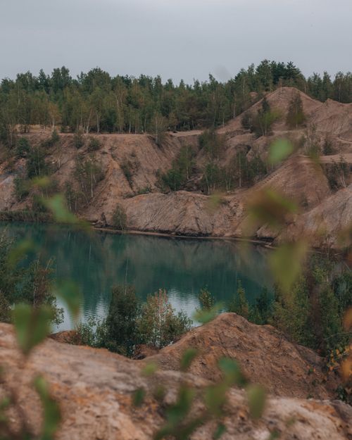 Free Peaceful landscape featuring lush green trees and a serene lake surrounded by natural cliffs. Stock Photo