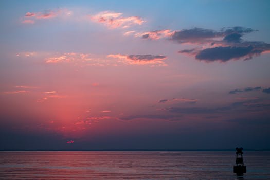 Beautiful ocean sunrise with a vivid pink and blue sky, creating a dramatic horizon over calm waters.
