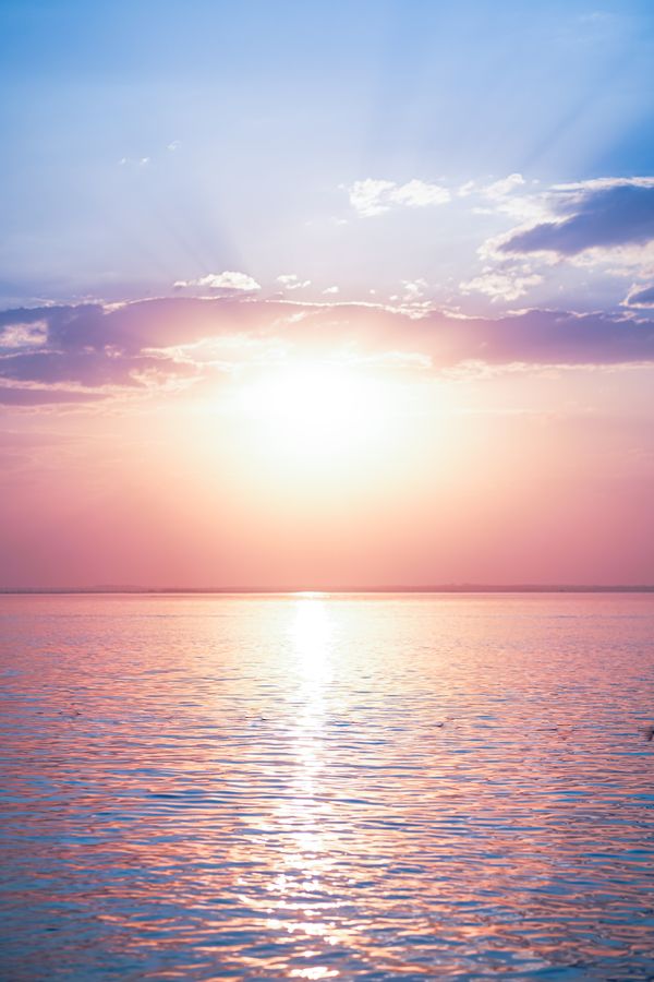 Lindo nascer do sol sobre águas calmas do oceano com um céu dramático, perfeito para fundos tranquilos.