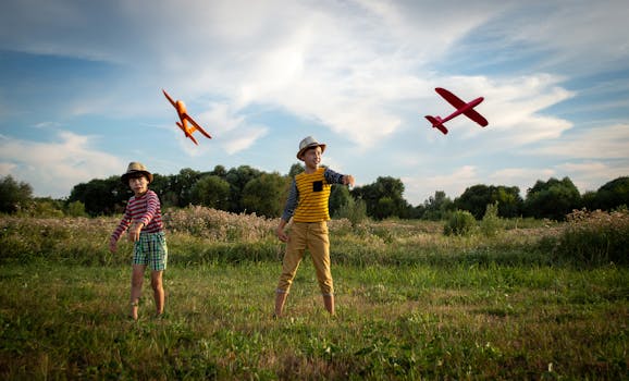 Two kids enjoying a sunny day outdoors, playing with toy airplanes.