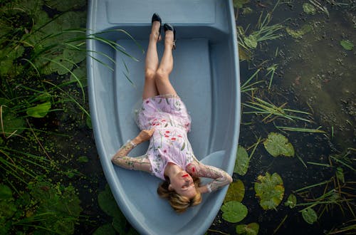 Free Woman in Pink Floral Dress Lying on Gray Boat Stock Photo