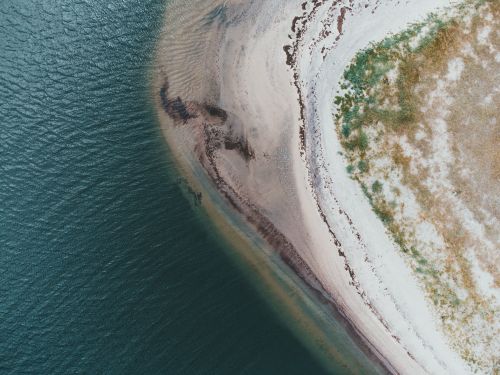Free Stunning aerial capture of a coastline with ocean waves and sandy beach. Stock Photo