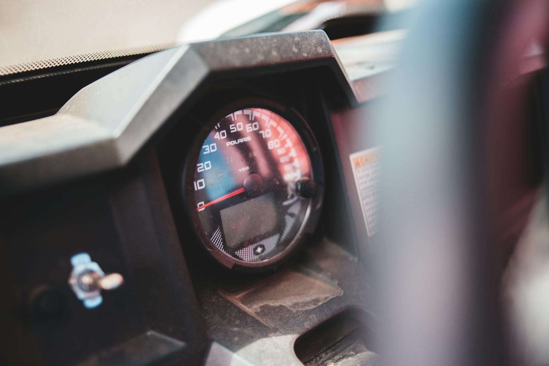 Detailed view of a speedometer showing kilometers per hour in a vehicle dashboard setting.